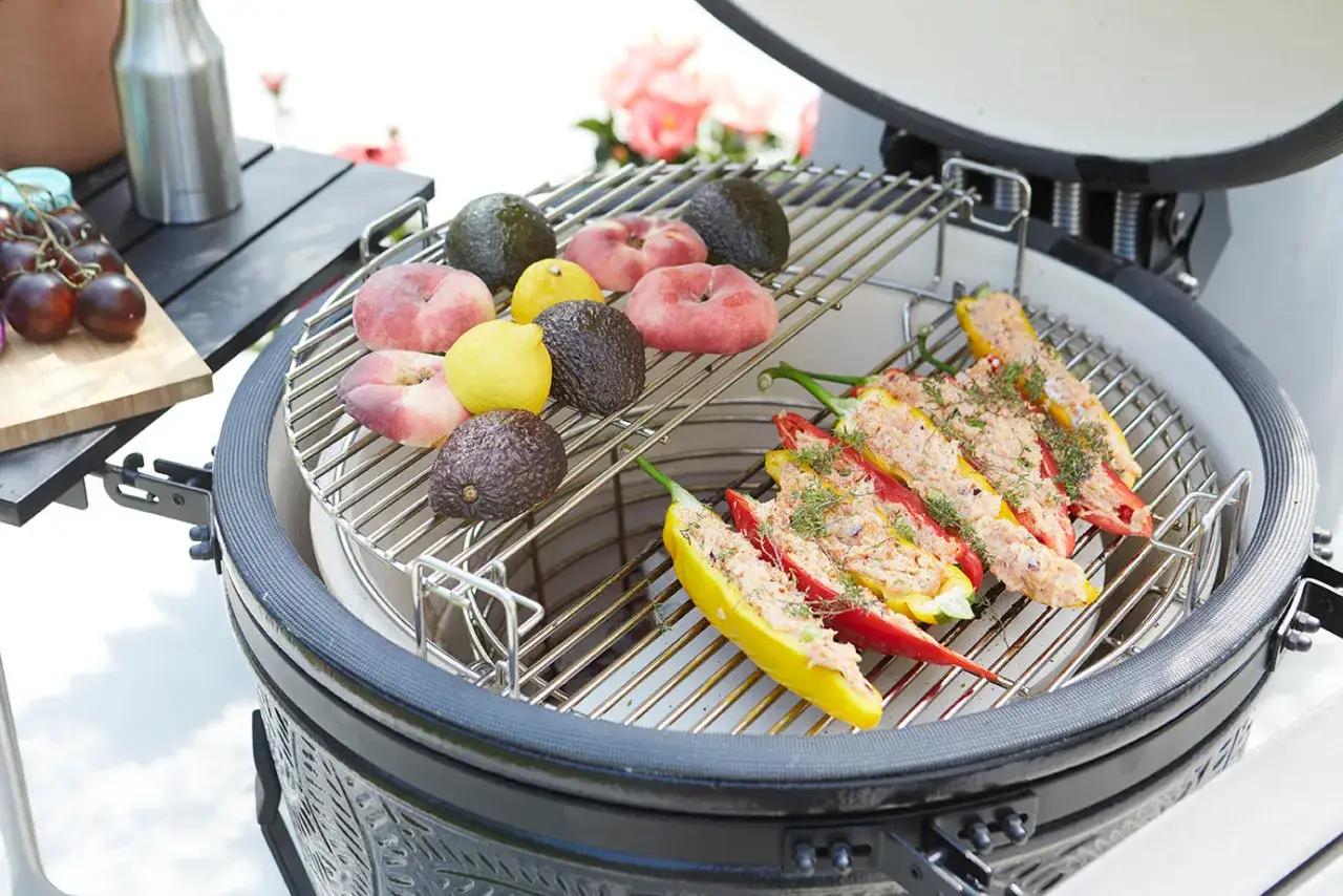 Poivrons farcis et fruits sur un kamado. Avis positif pour ce barbecue, idéal pour des grillades variées.