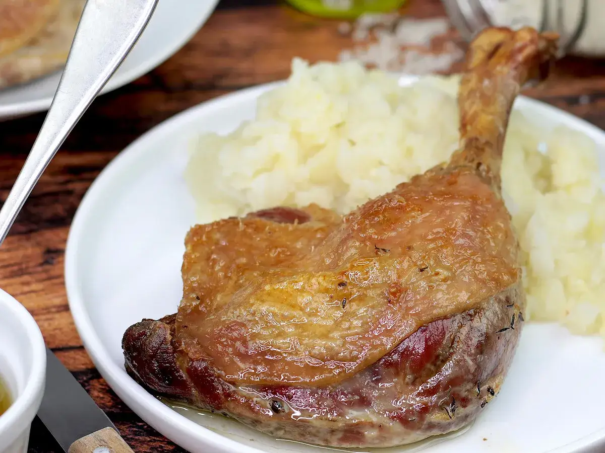 Une délicieuse cuisse de canard confite, dorée et juteuse, servie avec une purée onctueuse. Un plat savoureux prêt à être dégusté.