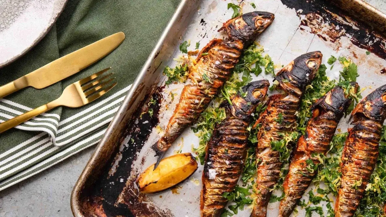 Sardines grillées sur plaque, parsemées de persil. Le temps cuisson sardine barbecue gaz est parfait pour ce plat savoureux.