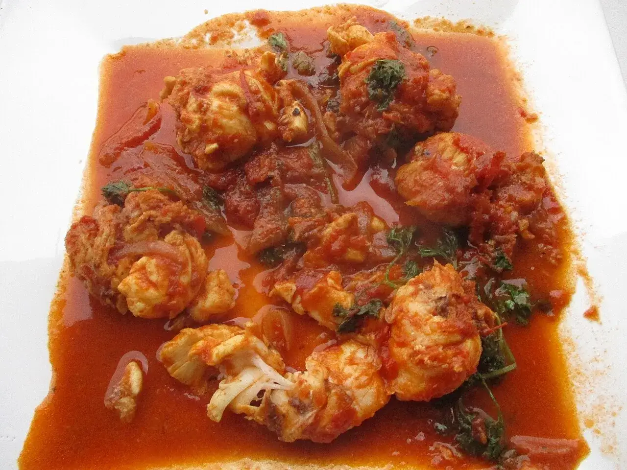 Morceaux de poisson enrobés d'une sauce armoricaine savoureuse, avec des herbes vertes parsemées.