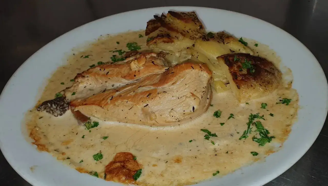 Un plat gourmand de poulet aux morilles à la crème, servi avec des pommes de terre rôties et parsemé de persil frais.