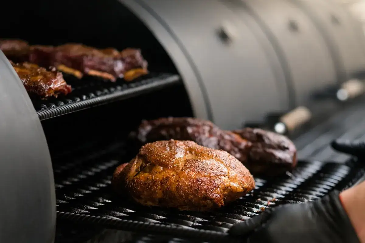 Un barbecue hivernal avec des côtes levées et un poulet rôti sur une grille.