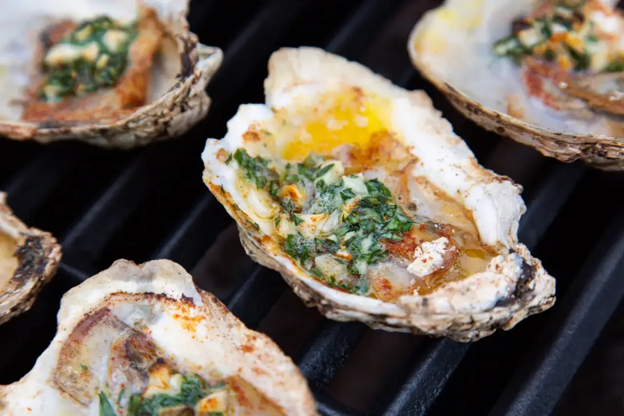 Huitres au barbecue, garnies d'herbes et de beurre fondu, grésillant sur le grill. Un délice fumé.