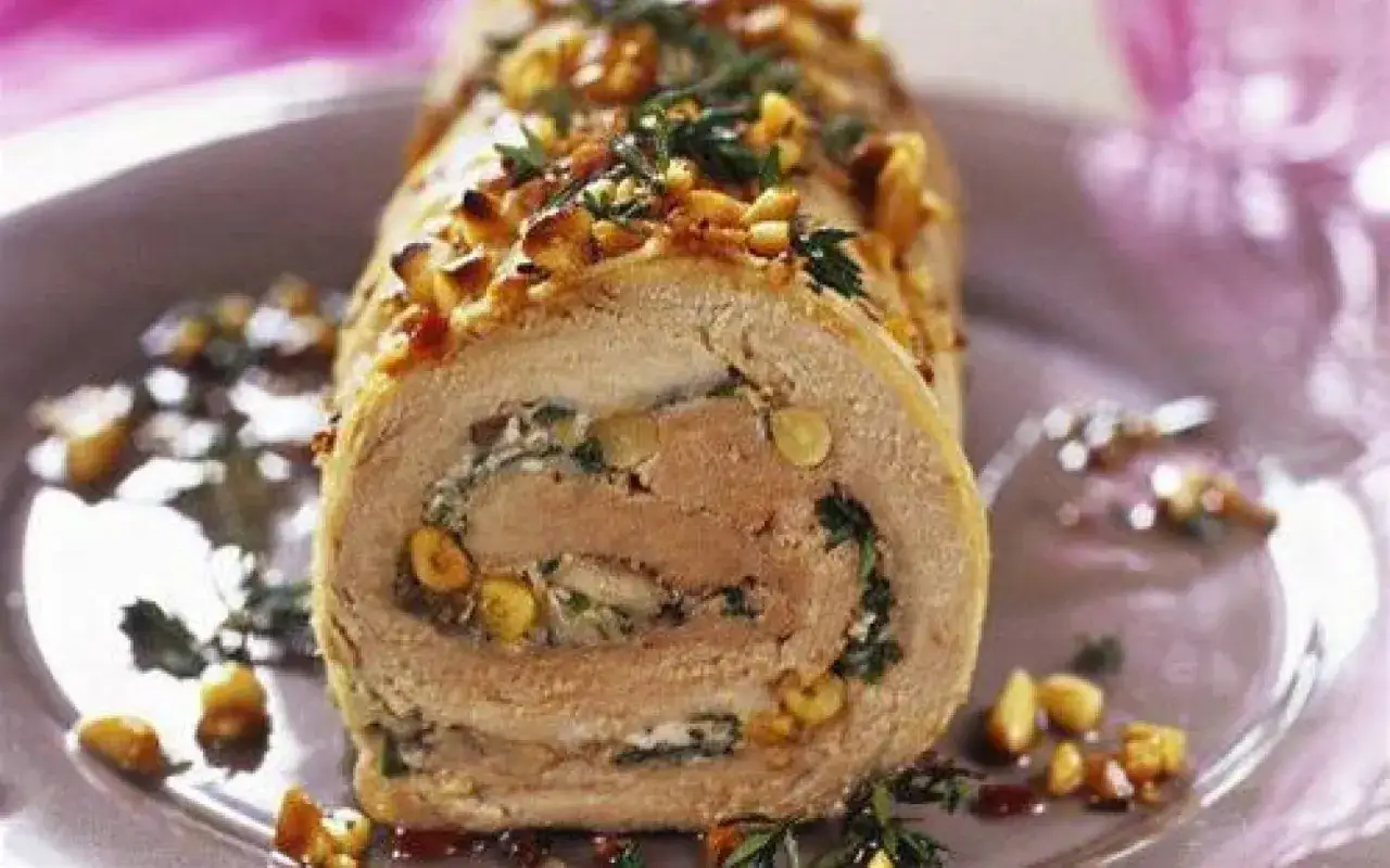 Délicieuse roulade de porc garnie d'herbes et de noix, servie sur une assiette décorée.