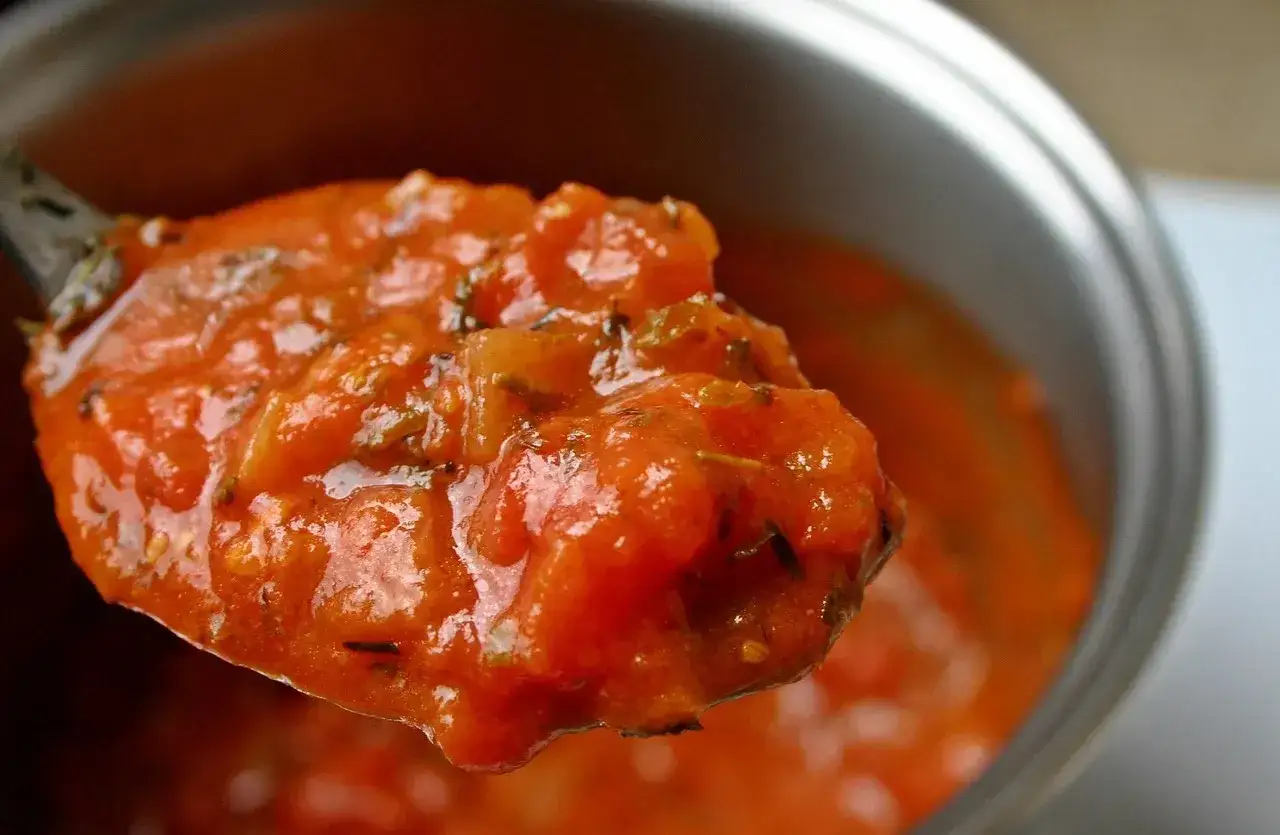 Une cuillère débordante de sauce tomate maison, riche et parfumée, prête à sublimer vos plats.