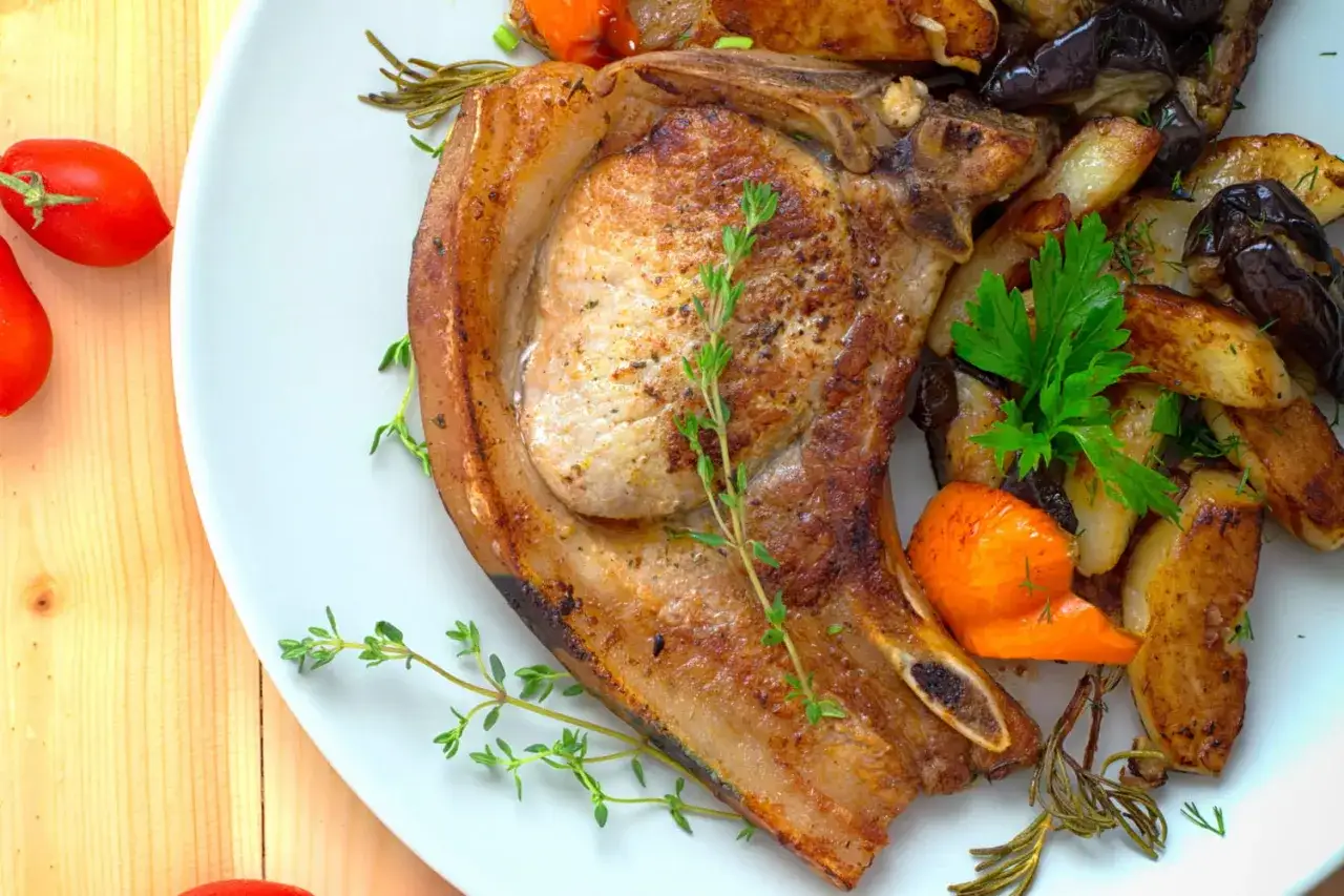 Une côte de porc barbecue juteuse, accompagnée de légumes rôtis et d'herbes fraîches. Un délice pour les amateurs de grillades.