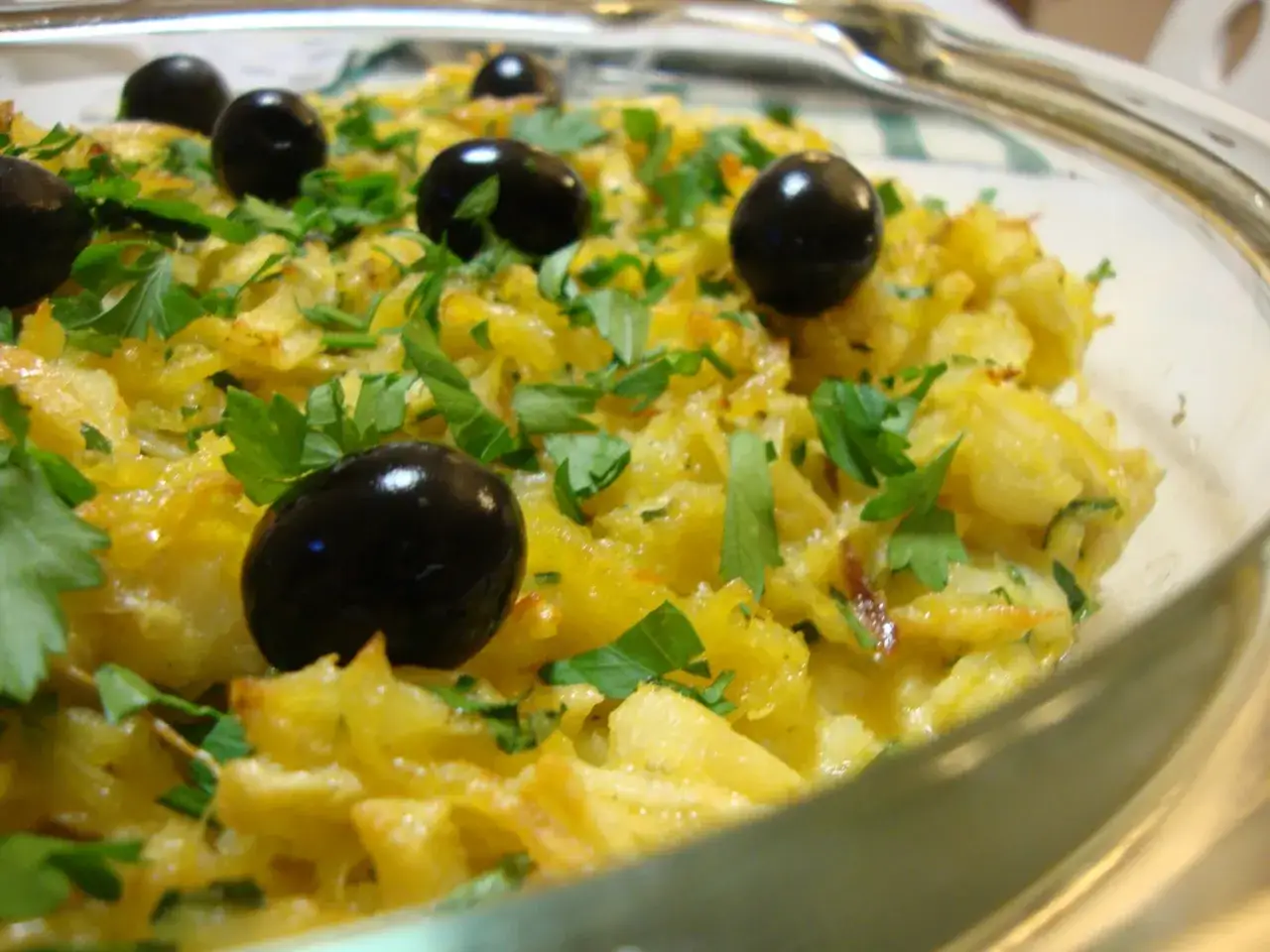 Un plat de bacalhau &agrave; br&aacute;s, garni d'olives noires et de persil frais, pr&ecirc;t &agrave; &ecirc;tre d&eacute;gust&eacute;.