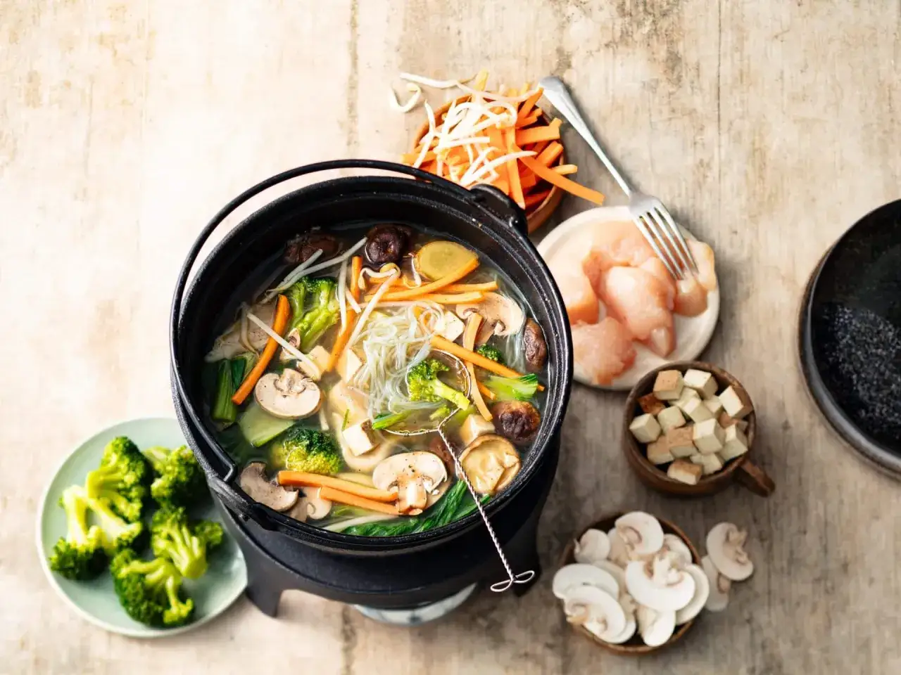 Une fondue sans huile bouillonnante avec des légumes, des nouilles et du poulet. Parfait pour un repas sain et savoureux.