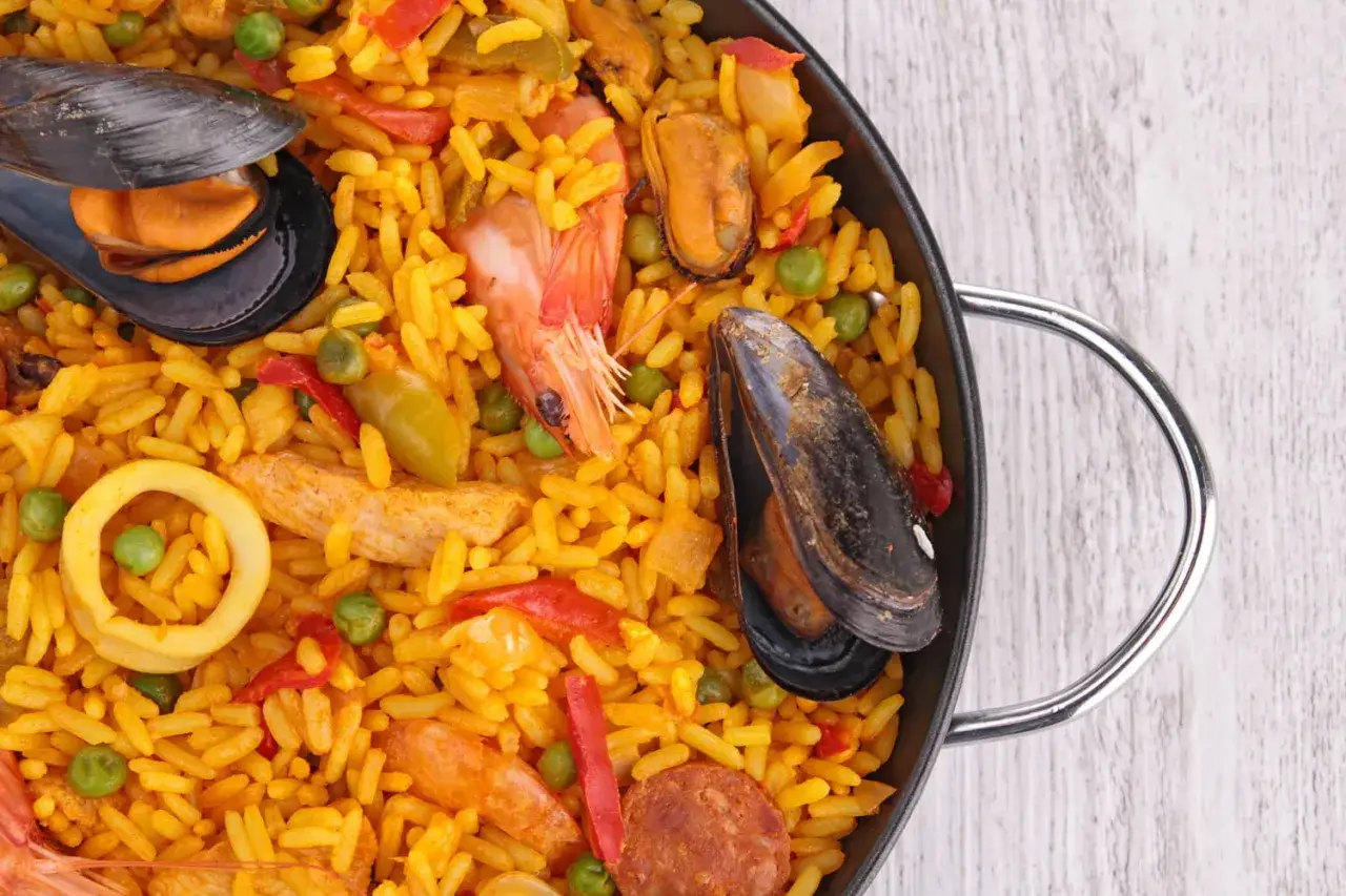 Un plat de paella royale d&eacute;bordant de riz safran&eacute;, de moules, de crevettes, de calamars et de chorizo.