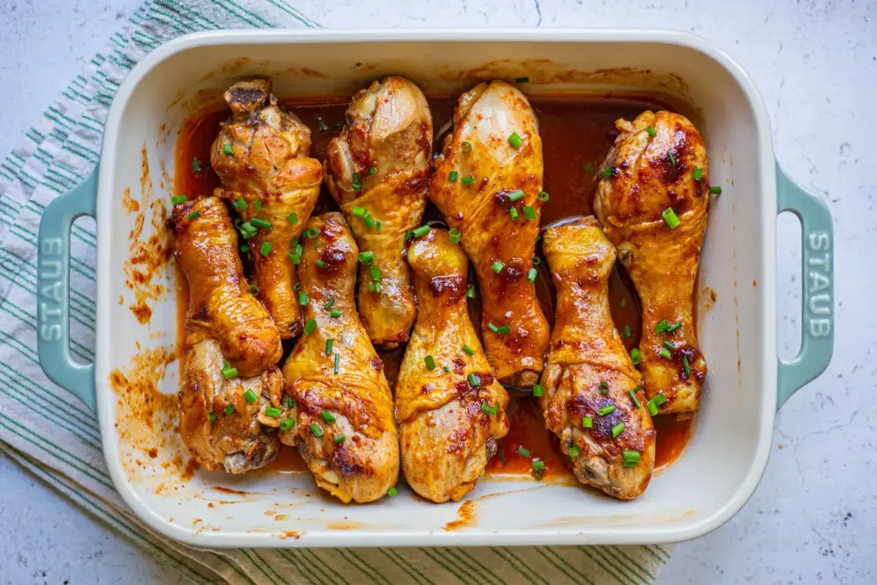 Un plat de pilon de poulet, dorés et brillants, garnis de ciboule fraîche. Un délice prêt à être dégusté.