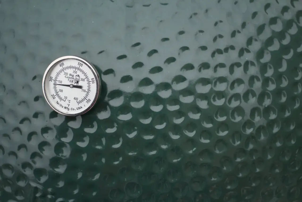 Thermomètre sur un kamado vert, indiquant la température pour une cuisson parfaite.