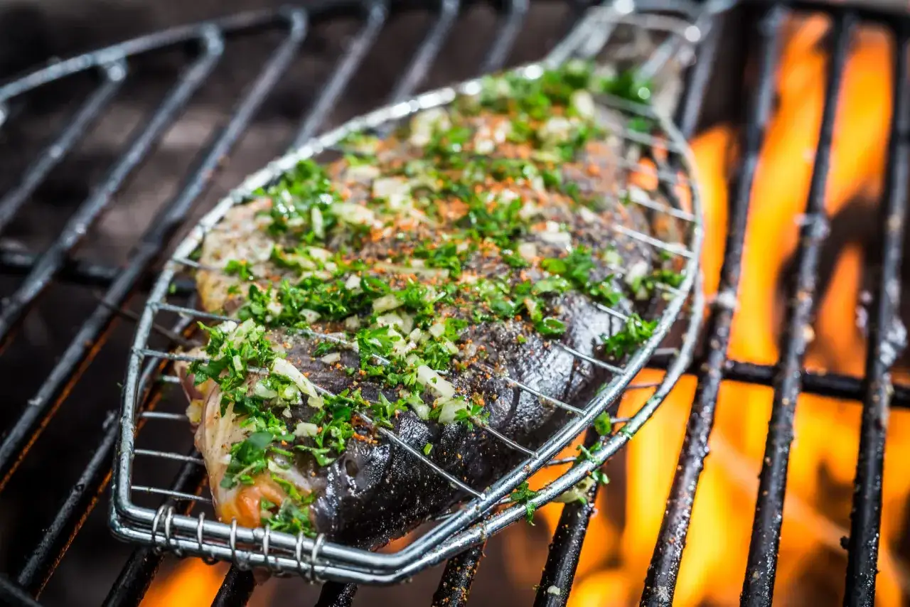 Un poisson entier, assaisonné d'herbes et d'épices, cuit sur un gril au-dessus de flammes vives. Quel poisson barbecue !