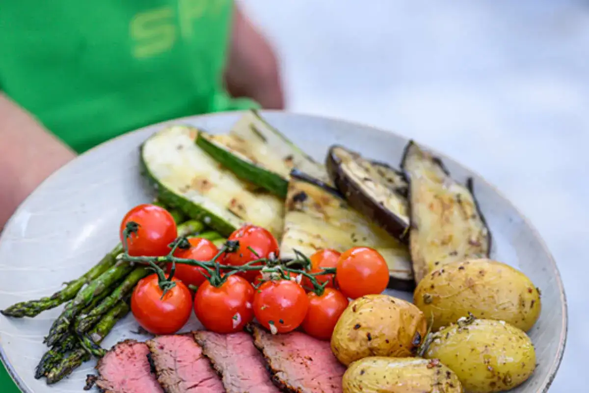 Assiette de viande rouge grillée avec des légumes parfaits : courgettes, aubergines, tomates cerises, asperges et pommes de terre. Idéal pour savoir quels légumes pour accompagner une viande rouge.