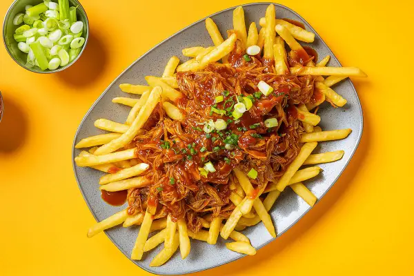 Frites croustillantes nappées d'une généreuse portion de pulled pork sauce barbecue, garnies de ciboule fraîche. Un délice !